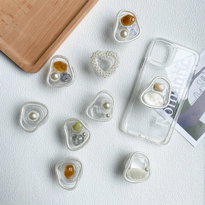 Close-up of elegant marble and pearl telescopic phone socket grips on clear phone cases