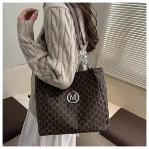 Détail du grand cabas avec imprimé monogramme M marron et plaque logo métallique