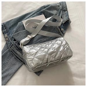 Detail of silver quilted metallic shoulder bag with adjustable strap on denim jacket