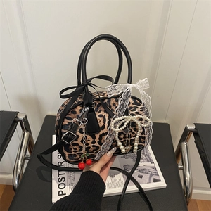 Borsa a tracolla leopardata con fiocco in pizzo e ciondolo a ciliegia su rivista