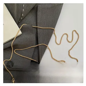 Detail of elegant gold metal chain strap and polished oversized handle on a luxury evening bag