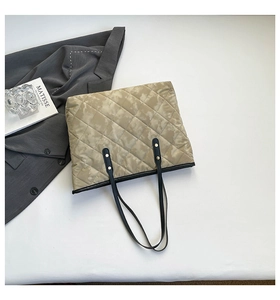Detail of quilted tote bag with camo print, thin black straps and metal rivets