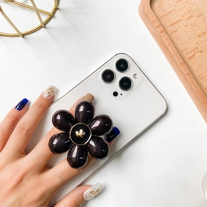 Close-up of black flower phone socket with a gold heart detail on a white phone case