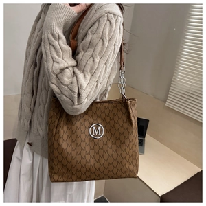 Détail du sac cabas marron avec motif monogramme M et bandoulière en chaîne argentée