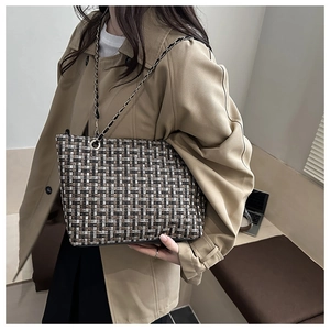 Detail of tweed tote bag with woven black gold chain strap and textured fabric