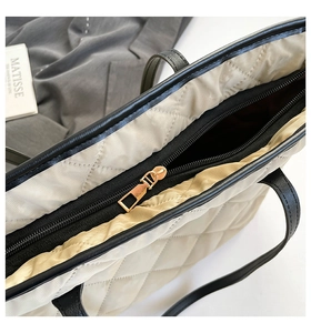 Detail view of large quilted tote bag featuring beige nylon and black leather accents