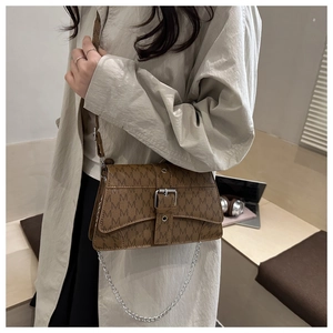 Detail of a brown leather shoulder bag with vintage M-pattern print and silver buckle