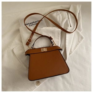 Detailed close-up of brown leather handbag with gold twist lock and handle on knit fabric