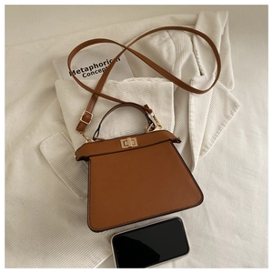 Detailed view of brown leather handbag with gold twist lock and adjustable strap