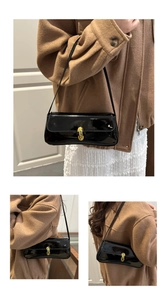 Detailaufnahme einer glänzenden schwarzen Lackledertasche mit goldenem Drehverschluss