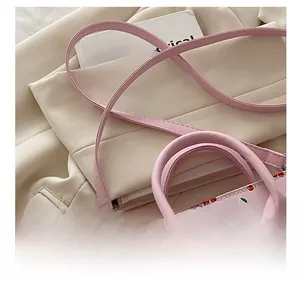 Dettaglio della tracolla regolabile su borsa in pelle PU rosa con motivi ciliegia