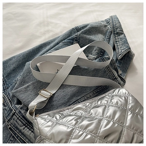 Detail of silver quilted tote bag with metallic finish on blue denim jacket
