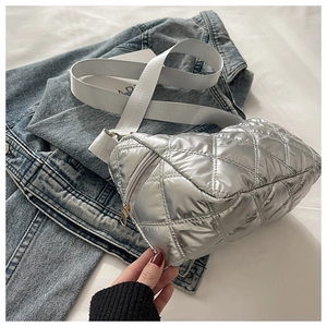Detail of silver quilted cross-body bag featuring a metallic finish and wide strap