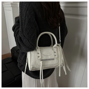 Rear view of a white leather pillow bag with silver studs on a stylish model