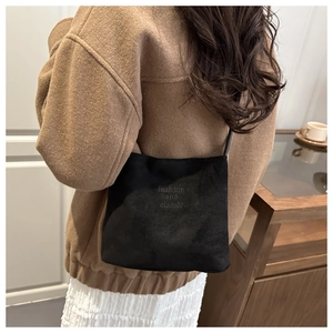 Detailed view of black suede-textured shoulder bag with fashion and classic engraving
