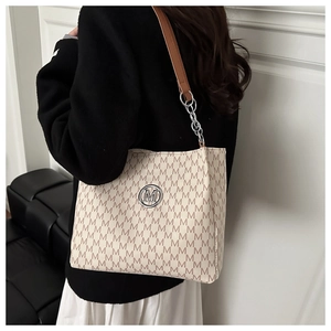 Détail d'un grand sac cabas avec bandoulière en cuir marron et chaîne sur personne