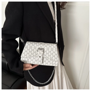 Close-up of white crossbody bag with grey M-letter print and silver chain strap