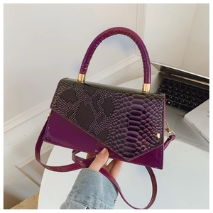 Detail of purple faux crocodile texture handbag with gold metal hardware and top handle