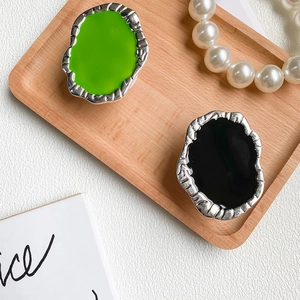 Detailed view of irregular liquid metal phone grip in neon green and black on wood