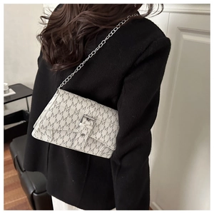 Detail of a vintage-style shoulder bag with chain strap and elegant monogram print