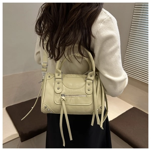 Detailed shot of cream motorcycle bag with silver studs and long leather tassels