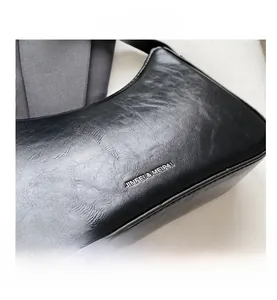 Detailed close-up of textured black shoulder bag featuring silver metal logo detail