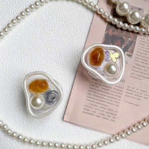 Detail of Korean style cream glue phone grip with pearls and resin butterfly on white texture