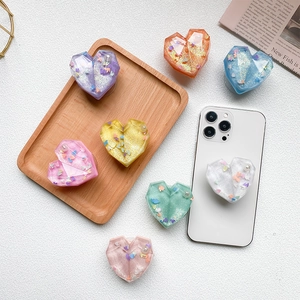 Detail of heart-shaped glitter resin phone grips with pearls in multiple colors