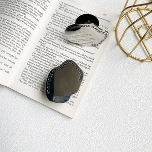Detail of silver and black metallic phone grips with engraved motivational quotes on a book