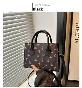 Close-up of black tote bag with cherry print held in a stylish indoor setting