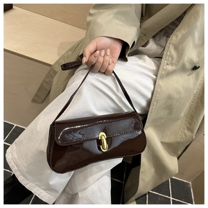 Detail einer dunkelbraunen Lackleder-Schultertasche mit goldenem Drehverschluss