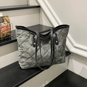 Chic grey quilted tote bag with black straps and gold rivets for casual commuting