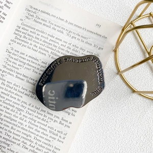 Detail of silver metallic phone grip featuring engraved motivational quotes on mirror surface