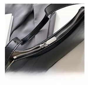 Detail shot of the smooth silver metal zipper and textured black leather surface