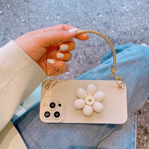 Detail of cream iPhone case featuring a 3D white flower stand and gold chain strap