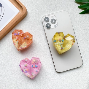 Macro detail of heart-shaped phone grips featuring colorful sequins and glitter inside