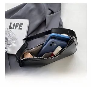 Detailed interior view of black underarm bag showing capacity for phones and cosmetics