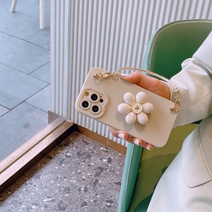 Close-up of cream iPhone case with a 3D white flower and a golden chain handle