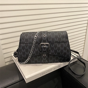 Retro black underarm bag with M-pattern monogram and silver chain strap on a white book