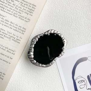 Artistic irregular silver metal phone grip with black enamel inlay on leather background