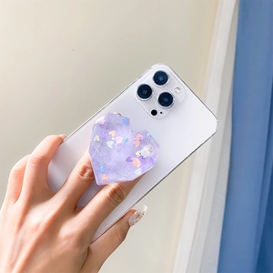 Purple glitter heart phone socket grip with resin sequins on a white smartphone
