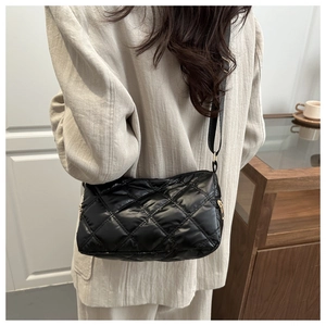 Rear view of model wearing a black quilted puffer crossbody bag with a gold zipper