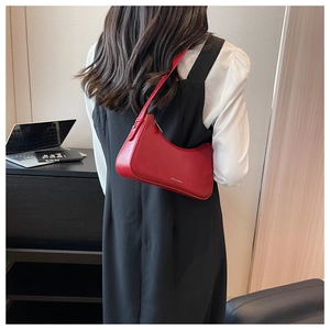 Chic red leather underarm bag worn by model in a minimalist modern setting