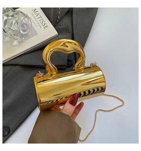 Close-up of a gold mirror-finish capsule bag with a unique sculptural handle and chain