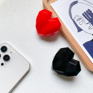 Detail of 3D geometric heart phone sockets in glossy red and black on a white surface