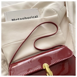 Nahaufnahme der weinroten Lackleder-Schultertasche mit vintage goldenem Metallschloss