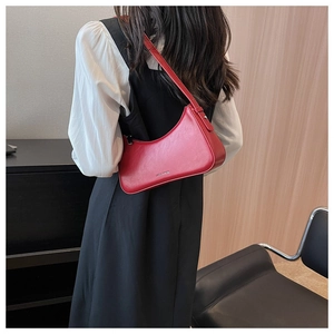 Close-up of a red leather baguette bag with JMLIA&MUKU branding worn over the shoulder