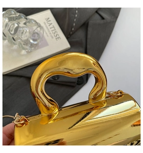 Macro detail of high-end metallic gold handbag with thick curved top handle design