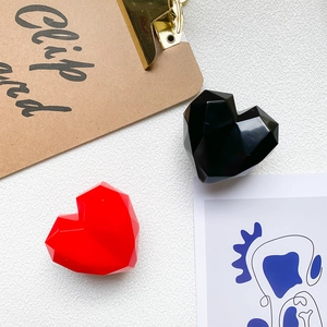 Close-up of geometric heart-shaped phone grip with faceted red and black glossy finish