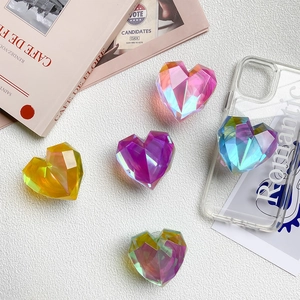 Colorful laser heart-shaped retractable phone grip stands on white leather background